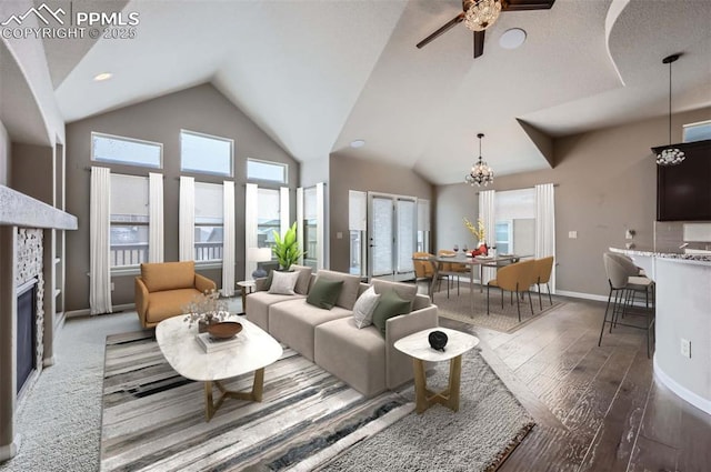 living room featuring ceiling fan with notable chandelier, dark hardwood / wood-style flooring, a tile fireplace, and a wealth of natural light