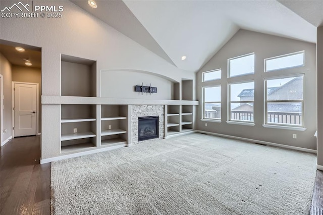 unfurnished living room with lofted ceiling, built in features, and a stone fireplace