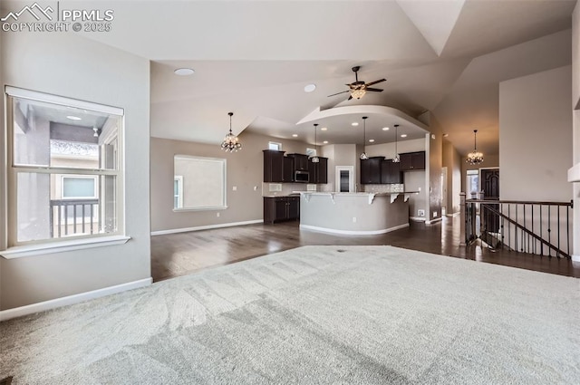 unfurnished living room with lofted ceiling and ceiling fan with notable chandelier