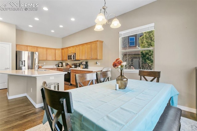 dining space with sink, dark hardwood / wood-style floors, and an inviting chandelier