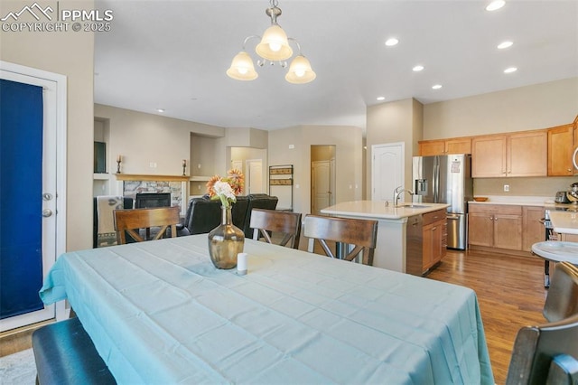 dining space with a fireplace, light hardwood / wood-style flooring, and sink