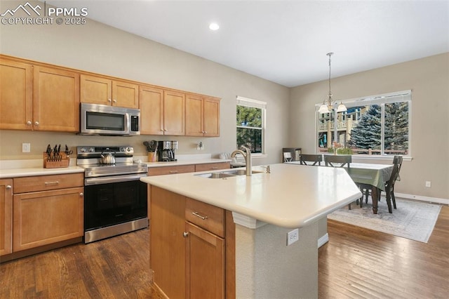 kitchen with sink, stainless steel appliances, dark hardwood / wood-style floors, decorative light fixtures, and a kitchen island with sink