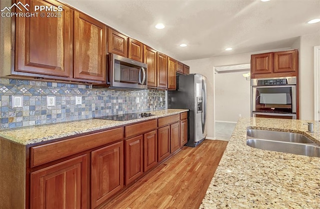 kitchen featuring sink, stainless steel appliances, light hardwood / wood-style floors, and light stone countertops