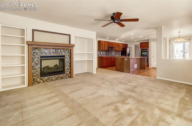 unfurnished living room featuring built in shelves, ceiling fan, and a multi sided fireplace