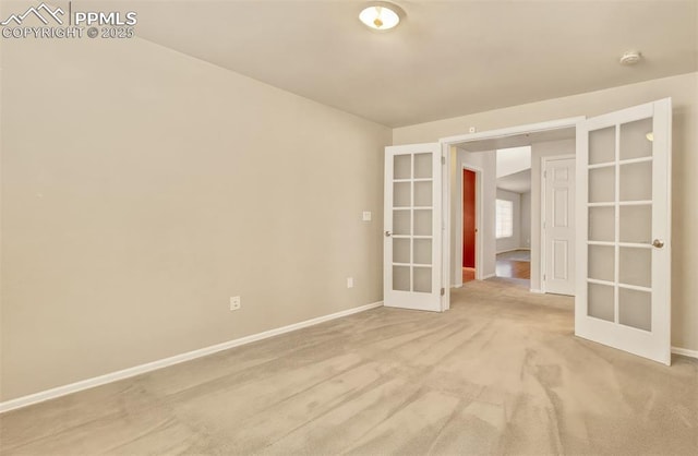 empty room featuring french doors and light colored carpet