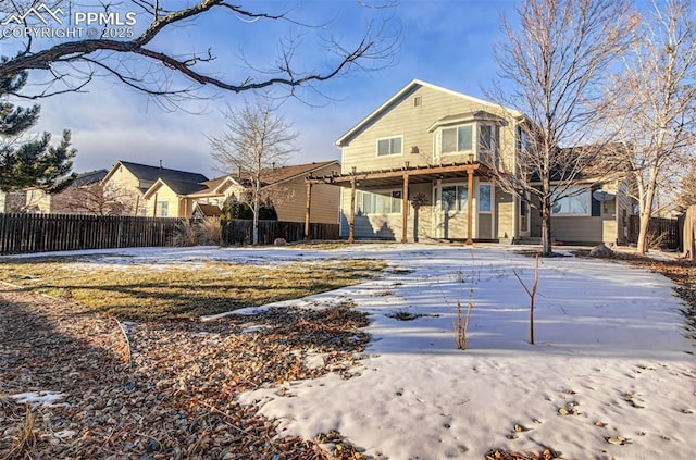 snow covered rear of property featuring a pergola