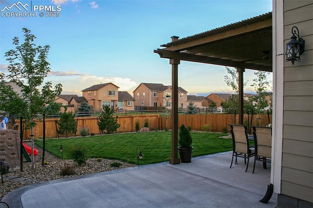 patio terrace at dusk featuring a lawn