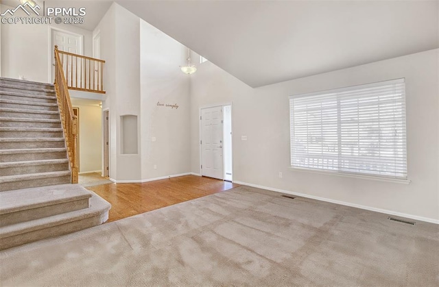 entrance foyer with high vaulted ceiling and carpet flooring