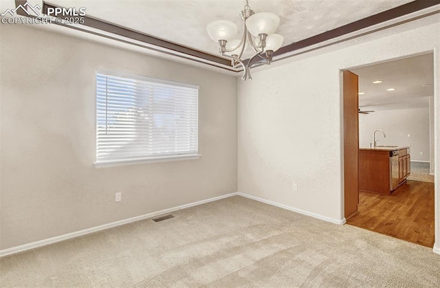 carpeted spare room with sink and ceiling fan with notable chandelier