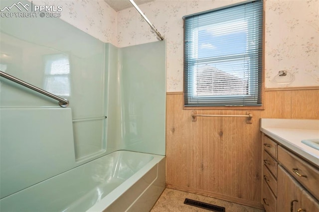 bathroom with tub / shower combination, wood walls, and vanity