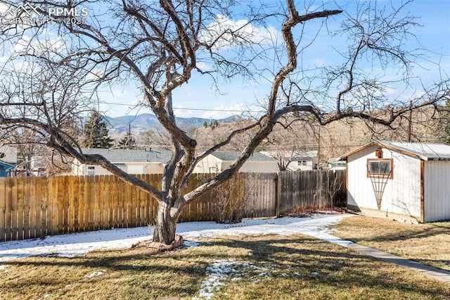 yard layered in snow featuring a shed and a mountain view