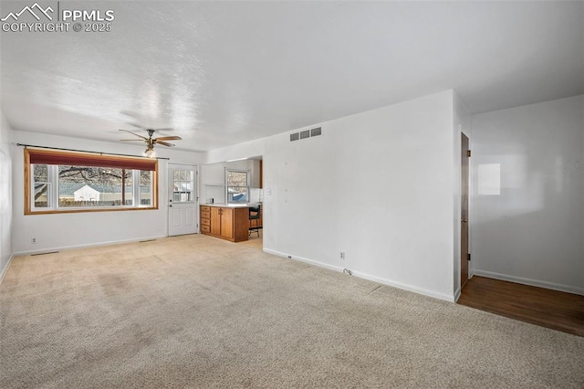 unfurnished living room with light carpet and ceiling fan