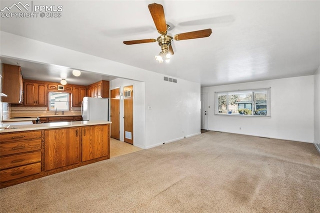 kitchen featuring ceiling fan, light colored carpet, and refrigerator