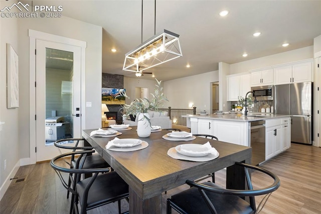 dining area with a large fireplace, sink, and light hardwood / wood-style flooring