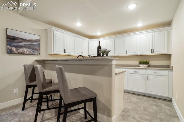 kitchen featuring a breakfast bar area, white cabinetry, and kitchen peninsula