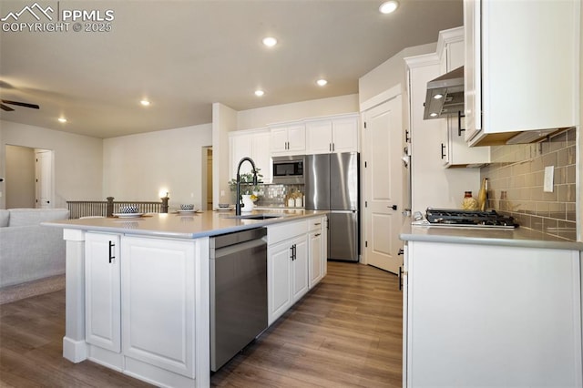 kitchen with white cabinetry, extractor fan, a center island with sink, stainless steel appliances, and sink