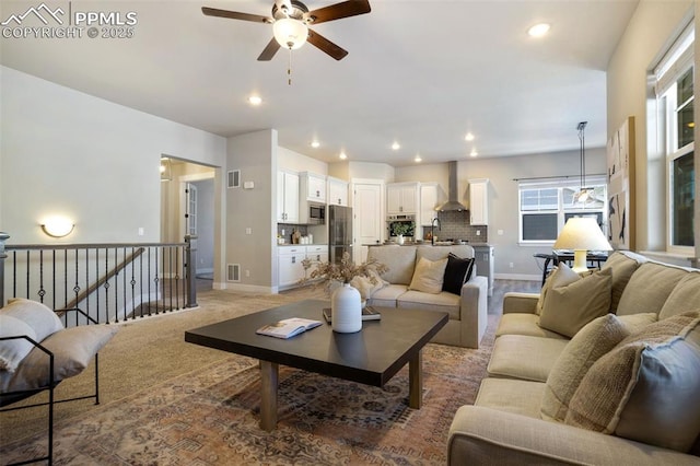 living room featuring ceiling fan, sink, and light colored carpet