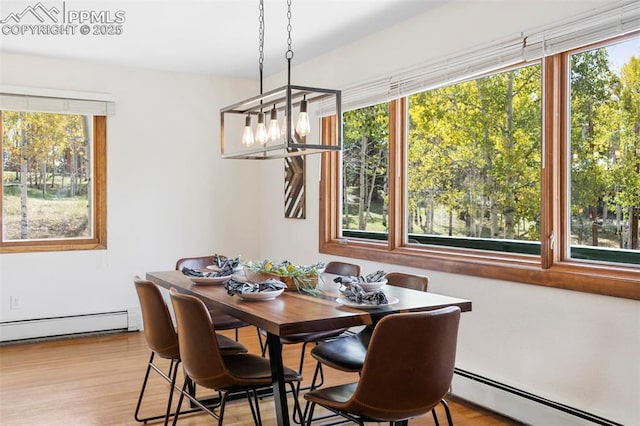 dining space with a baseboard heating unit, a chandelier, and light hardwood / wood-style floors