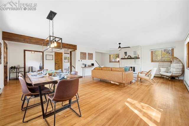 dining room with hardwood / wood-style flooring, ceiling fan with notable chandelier, and a fireplace