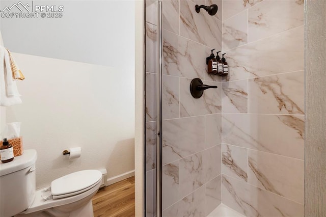 bathroom with wood-type flooring, a tile shower, and toilet