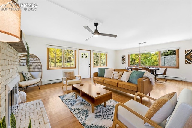 living room with a baseboard heating unit, a fireplace, light hardwood / wood-style floors, and ceiling fan