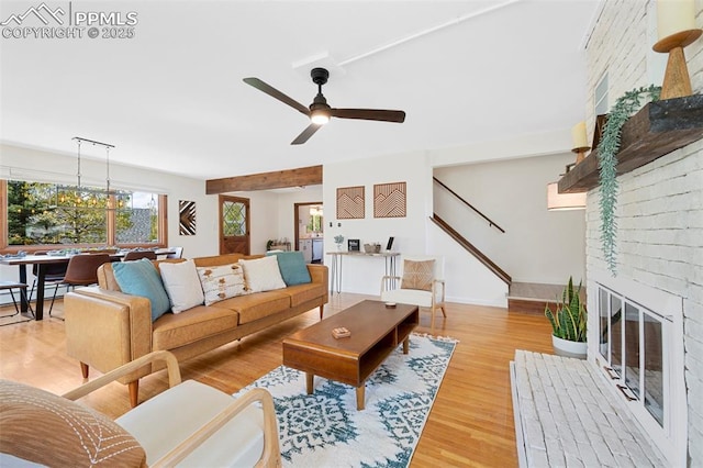 living room with ceiling fan, a fireplace, and light wood-type flooring