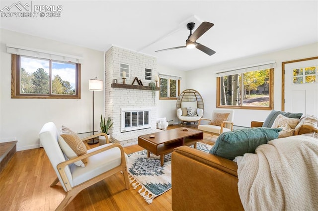 living room with a fireplace, light hardwood / wood-style floors, ceiling fan, and baseboard heating