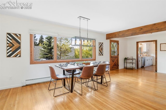 dining space featuring beamed ceiling, light hardwood / wood-style flooring, and a baseboard heating unit