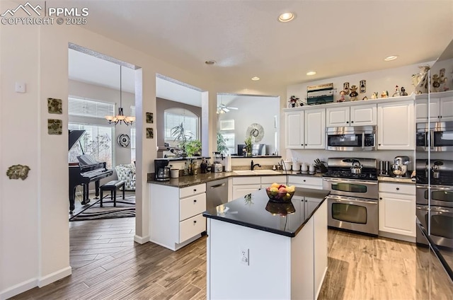 kitchen with sink, stainless steel appliances, white cabinetry, and light hardwood / wood-style flooring