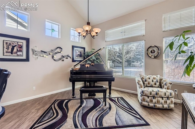 sitting room featuring light wood-type flooring, high vaulted ceiling, a wealth of natural light, and a notable chandelier