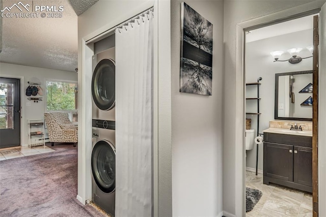 clothes washing area with a textured ceiling, sink, light colored carpet, and stacked washer / dryer