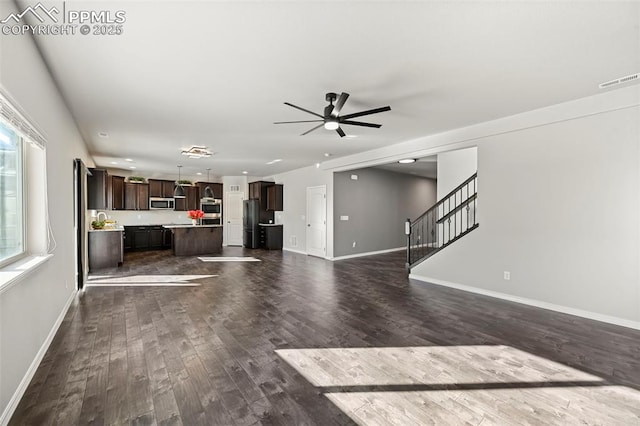 unfurnished living room with ceiling fan and dark wood-type flooring