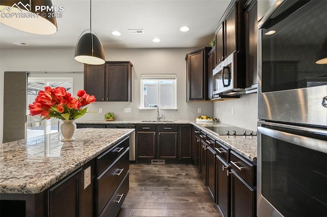 kitchen featuring pendant lighting, sink, light stone counters, dark hardwood / wood-style flooring, and stainless steel appliances