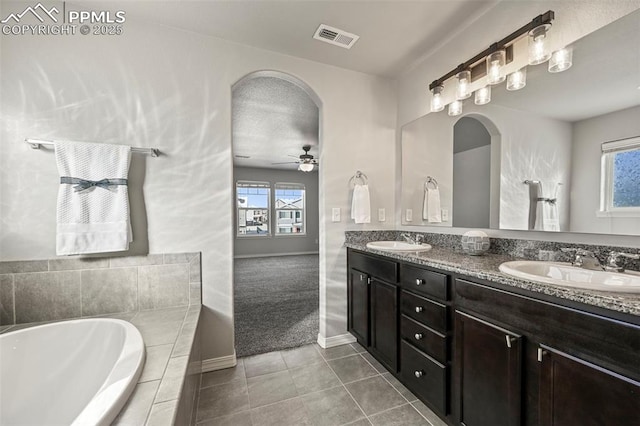 bathroom with ceiling fan, tile patterned floors, tiled bath, a textured ceiling, and vanity