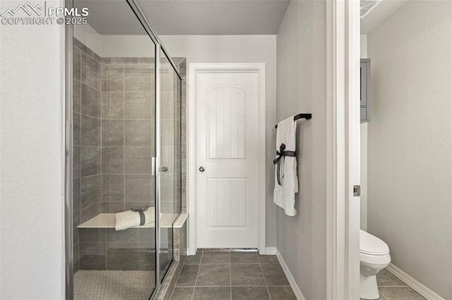 bathroom with tile patterned flooring, toilet, and a shower with shower door