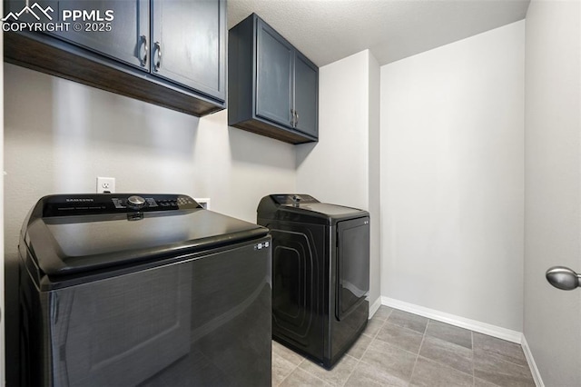 clothes washing area with separate washer and dryer and cabinets