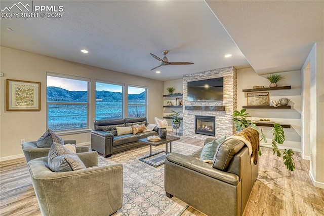 living room with ceiling fan, a fireplace, and light hardwood / wood-style flooring