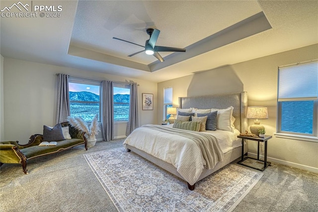 carpeted bedroom featuring ceiling fan and a tray ceiling