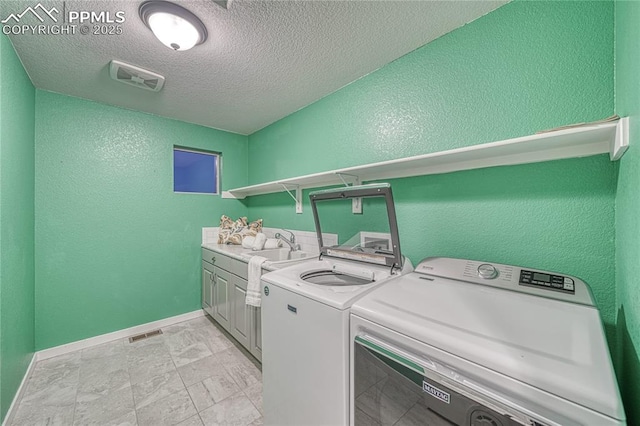 laundry area with cabinets, independent washer and dryer, a textured ceiling, and sink