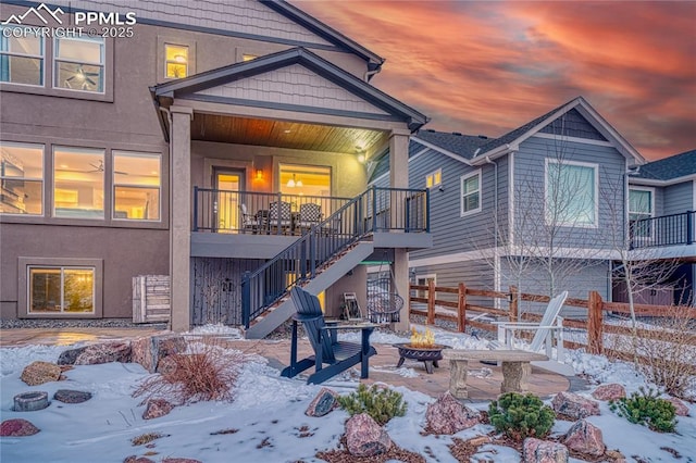 snow covered back of property with an outdoor fire pit