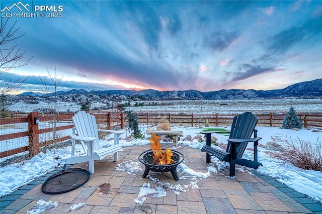 snow covered patio with a mountain view and an outdoor fire pit