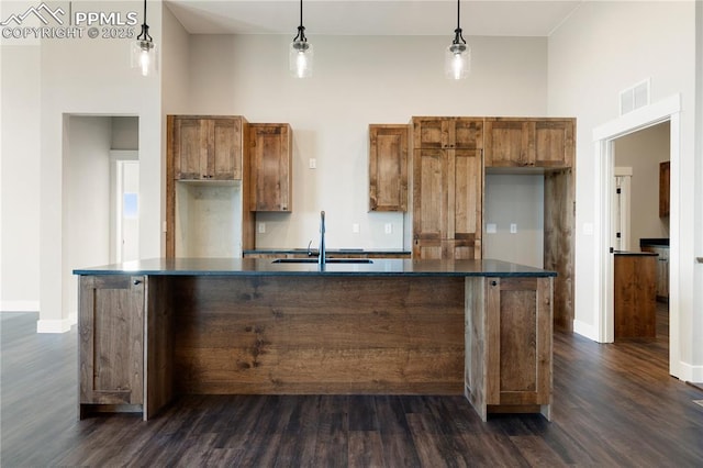 kitchen with sink, pendant lighting, a kitchen island with sink, and dark hardwood / wood-style floors