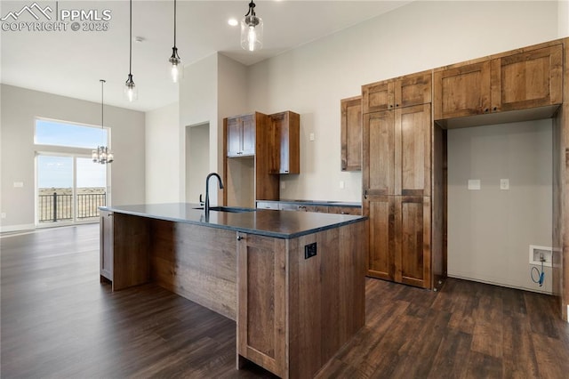 kitchen with sink, dark hardwood / wood-style flooring, an island with sink, and decorative light fixtures