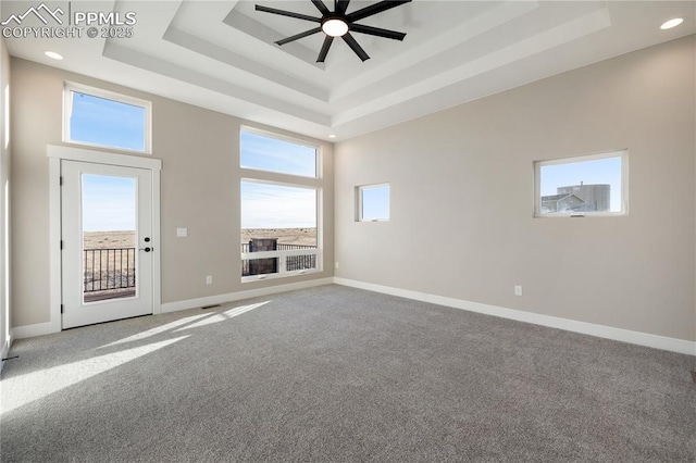 carpeted spare room featuring ceiling fan, a towering ceiling, and a raised ceiling