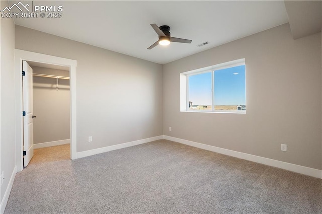 unfurnished bedroom with ceiling fan, a spacious closet, a closet, and light carpet