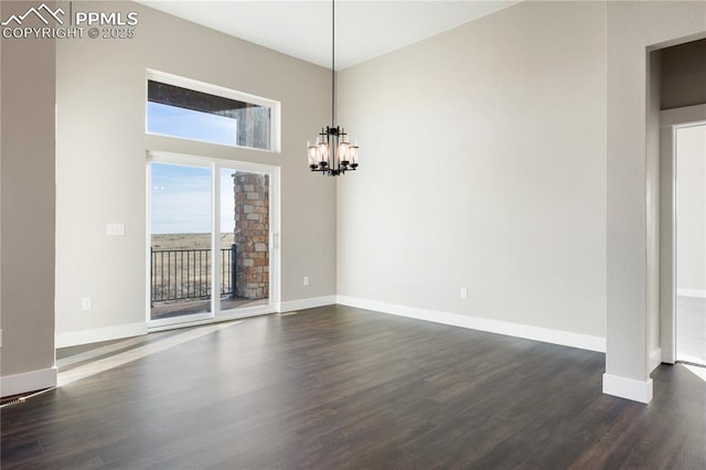 spare room with dark wood-type flooring and an inviting chandelier