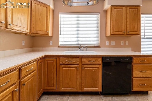 kitchen with sink, tile countertops, and dishwasher