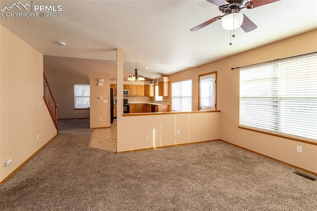 kitchen with sink, carpet flooring, black refrigerator, kitchen peninsula, and ceiling fan with notable chandelier