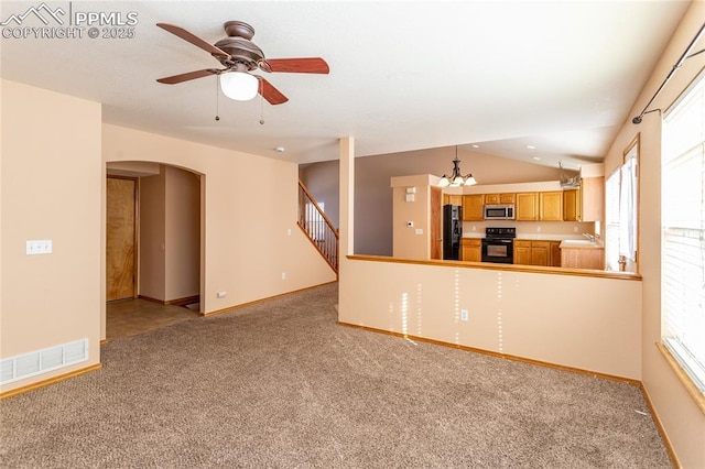 kitchen featuring vaulted ceiling, range, black refrigerator, ceiling fan with notable chandelier, and sink