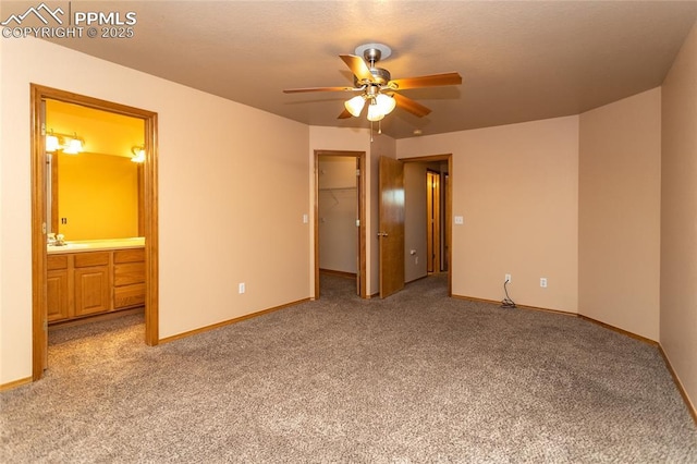 unfurnished bedroom with ensuite bath, a spacious closet, a closet, ceiling fan, and light carpet